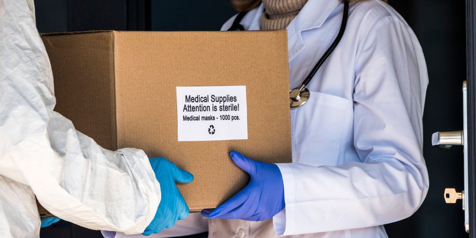 Medical supplies in a box carried by two people wearing white coats and globes