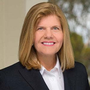 Headshot of Mary Long - smiling woman with shoulder-length blond hair in a dark blazer and a white button-up shirt.