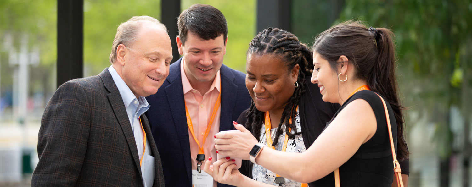 Group of people in business attire attending the Supply Chain Forum, looking at a photo