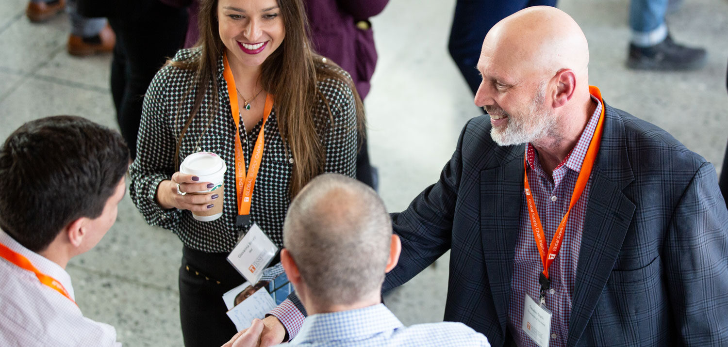 Group of people in business attire attending the Supply Chain Forum, smiling while listening to a speaker