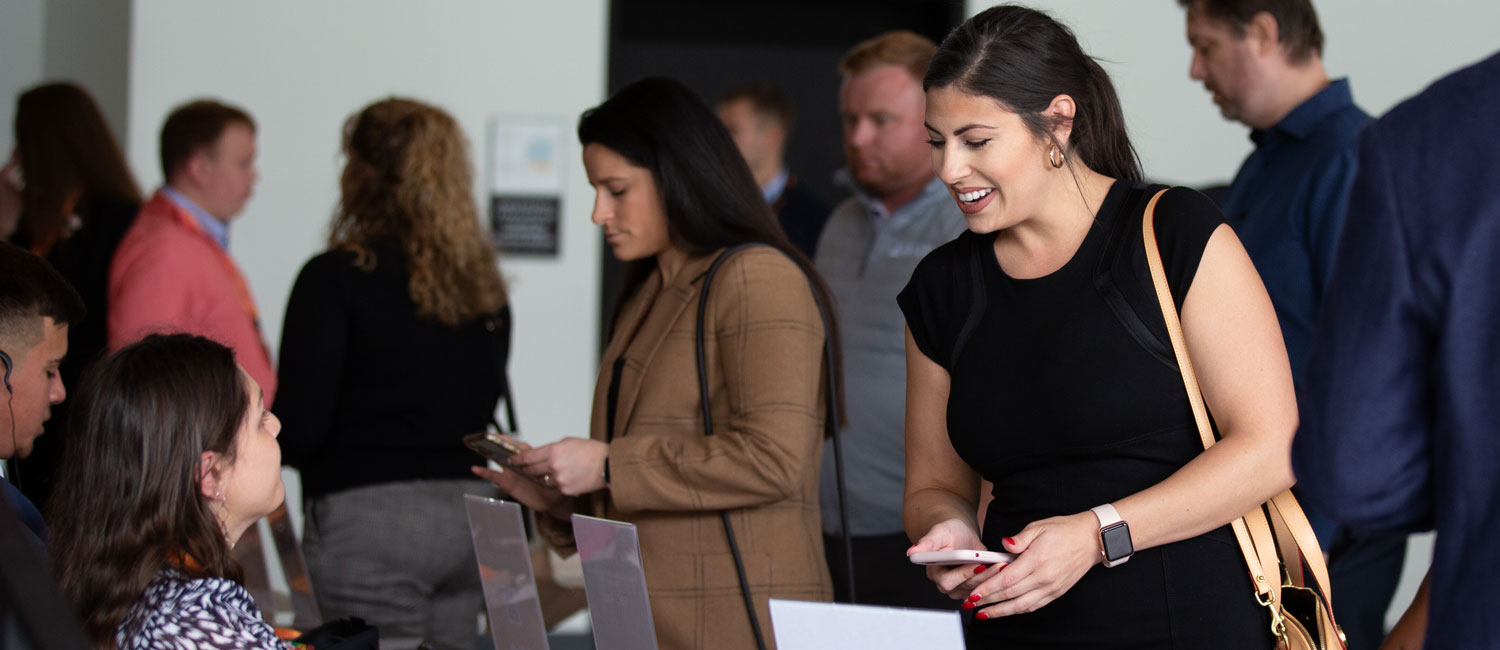 Group of people in business attire attending the Supply Chain Forum, smiling while listening to a speaker