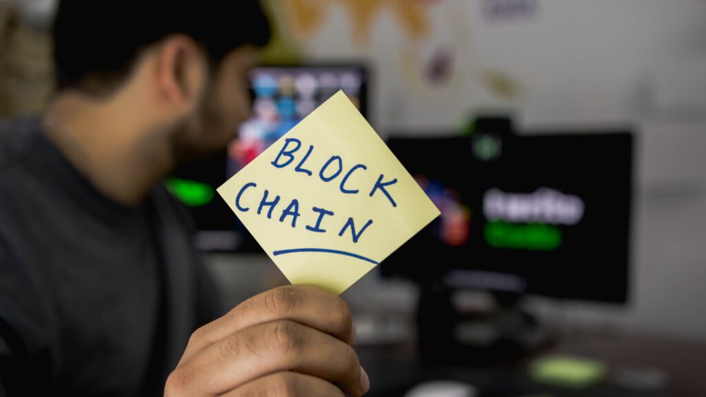 Image of a student holding a post-it note with "blockchain" written on it