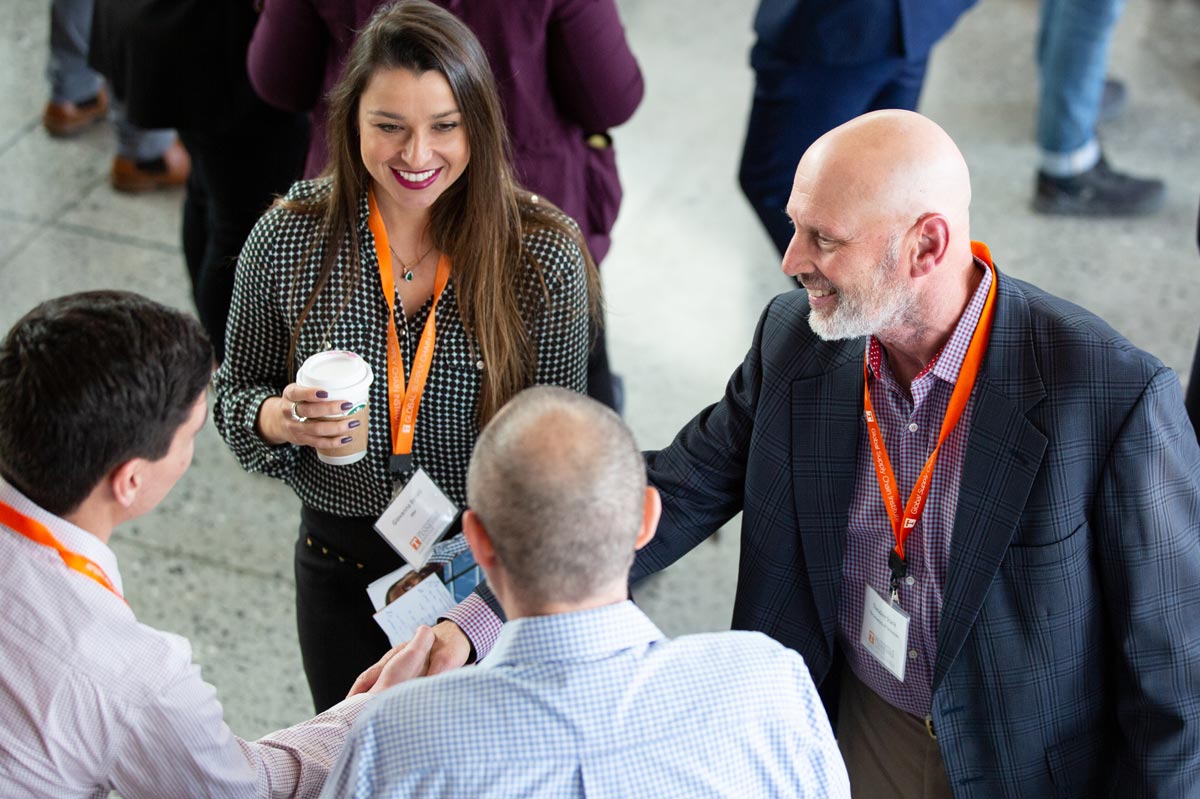 Supply chain professionals shake hands and smile during a networking session at the Supply Chain Forum.