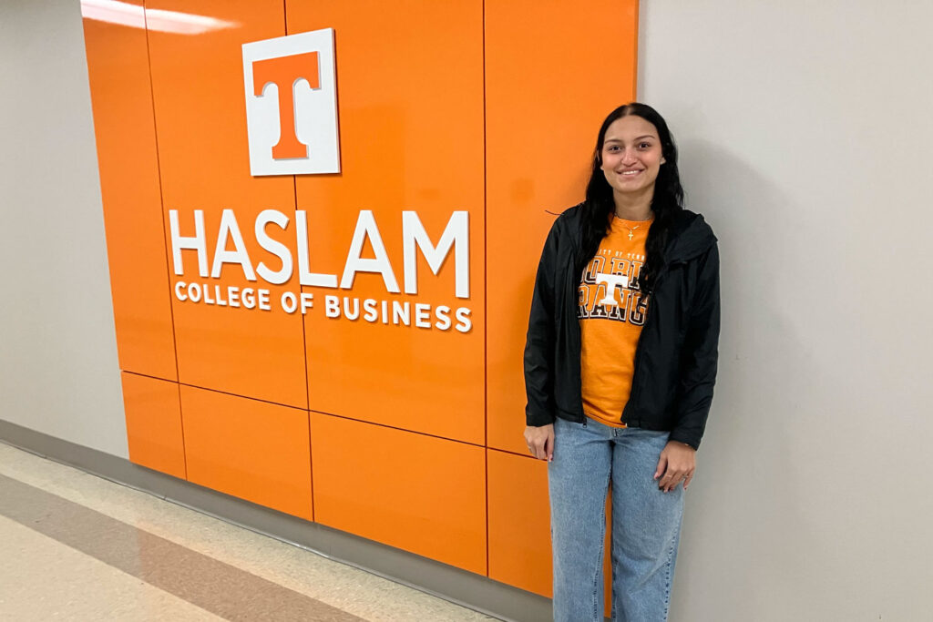 Student Sophia Torres-Colon poses in front of orange Haslam College of Business branding.